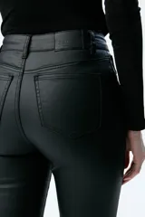 Pantalón de jean negro de tiro medio/alto con silueta levemente acampanada desde la rodilla.