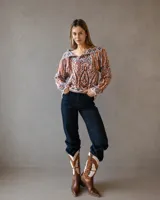 Sweater de punto con diseño étnico multicolor, cuello redondo y detalle de flecos en los hombros. Presenta mangas largas y un ajuste holgado.