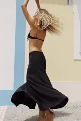 Falda larga de tiro alto, color negro, con diseño fluido y cintura elástica. Cierre lateral con cremallera oculta en costura.