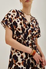 Vestido corto de escote cruzado en V, con mangas cortas tipo kimono y cintura elástica. Presenta un estampado animal print abstracto en tonos marrones, azul oscuro y crema.