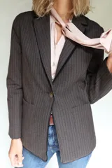 Blazer femenino forrado de corte tradicional, levemente entallado en la cintura, con mini hombreras, botón metálico con escudo y terminación desflecada.