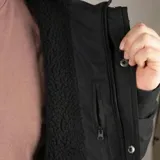 Campera Volcom de corte recto, color negro, con capucha ajustable, cierre frontal con solapa y botones a presión, bolsillos laterales con solapa y bolsillos superiores con cierre termosellado.