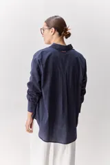 Camisa celeste de corte oversize, con mangas largas, cuello camisero y cierre frontal de botones.