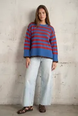 Sweater de punto con diseño de rayas horizontales en azul y rojo, cuello redondo y puños con terminación en color marrón.