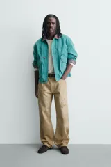 Pantalón straight fit de algodón con efecto lavado y roturas localizadas. Presenta diseño de cinco bolsillos, cierre frontal con cremallera y botón metálico.