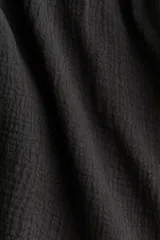 Top halter de algodon negro en muselina con escote en V y tiras que se anudan en el cuello. Presenta un diseño con costura fruncida debajo del busto y silueta acampanada.
