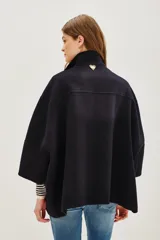 Tapado corto de paño en color azul marino, con cuello alto, cierre frontal de botones y mangas amplias de corte kimono. Presenta aberturas laterales en el ruedo y bolsillos frontales.