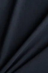 Remera de algodón de color negro, corte holgado con hombros caídos, cuello redondo acanalado y mangas cortas con doblez cosido.