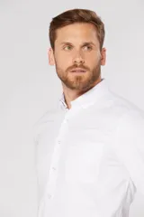 Camisa de vestir lisa color rosa claro, de manga larga, con cuello abotonado, bolsillo en el pecho y logo bordado.