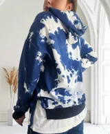Buzo con capucha color azul y blanco con estampado tie-dye, de corte holgado y mangas largas.