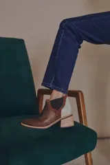 Botineta de diseño tricolor con cuerpo en tono beige, panel elástico lateral negro y talón con textura símil reptil en color marrón. Presenta un taco cuadrado robusto de color negro.