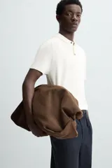 Polo de punto negro, manga corta, con cuello solapa y cierre frontal de tres botones. Presenta un calce regular y acabados en rib en mangas y ruedo.