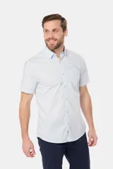 Camisa lisa de manga corta color crema, confeccionada en 100% algodón, con cuello abotonado y un bolsillo en el pecho.