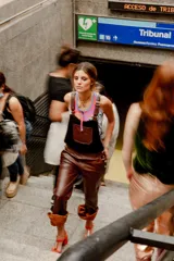 Enterito de estilo jardinera con cuerpo de corderito negro y pantalón de cuero marrón, con tirantes ajustables y bolsillos laterales.