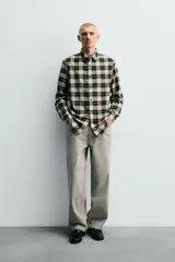 Camisa de corte relaxed fit confeccionada en una mezcla de lana y algodón. Presenta un diseño de cuadros, cuello solapa, manga larga con puños abotonados y cierre frontal con botones.