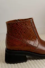 Bota corta de cuero marrón con panel trasero de gamuza en tono más oscuro, suela de goma negra y taco cuadrado bajo.