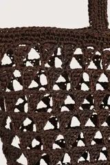 Bolsa tipo tote tejida en crochet con diseño de calados triangulares en color marrón oscuro. Cuenta con doble asa de hombro y un detalle de etiqueta colgante en cuero sintético color suela.