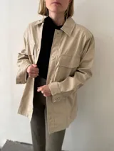 Sobrecamisa negra de ecocuero con cuello clásico, cierre frontal con botones, mangas largas y bolsillos de parche en el pecho.