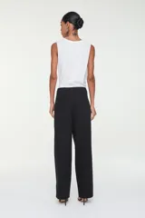 Pantalón negro de corte carrot, con bolsillos laterales, cierre frontal y aplicación de tachas metálicas en toda la prenda y en los dobladillos.