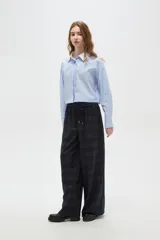 Pantalon de corte ancho y tiro alto, confeccionado en tela con estampado a cuadros en tonos verdes. Presenta cintura elástica con cordón de ajuste frontal.