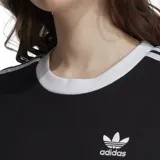Remera negra de Adidas con cuello redondo y mangas cortas con ribete blanco. Presenta las tres rayas blancas características de la marca en los hombros y el logo bordado en el pecho.
