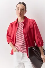 Camisa blanca de algodón, de calce relajado, con cuello camisero, frente abotonado y mangas largas abullonadas.