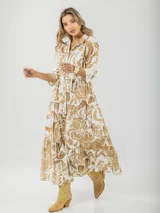 Vestido camisero midi de algodón con estampado floral en tonos rosados y blancos. Tiene cuello camisero, mangas 3/4, botones frontales, falda escalonada y cinturón fino.