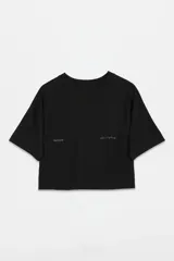 Remera cropped de algodón con efecto lavado, cuello redondo y mangas cortas. Presenta un pequeño estampado minimalista en el frente con texto y una carita sonriente con una lágrima.