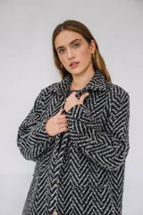 Tapado largo estilo chemise confeccionado en lana italiana tejida con patrón de espiga en color negro y gris. Presenta cierre frontal con botones y bolsillos con solapa.