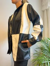 Campera con cierre frontal, diseño color block blanco y negro, cuello camisero y bolsillos laterales.