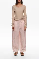 Pantalón jogger de tiro medio color rosado, confeccionado en mezcla de lyocell y algodón. Cuenta con cierre frontal oculto, bolsillos laterales y bajos ajustables con cordones elásticos y stoppers.