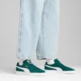 Championes Puma modelo Suede Classic, confeccionados en gamuza de color negro con la icónica franja lateral en blanco y el logotipo de la marca impreso en dorado metalizado en el lateral. Suela de goma texturizada en color blanco.