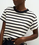 Blusa de corte boxy confeccionada en algodón, con diseño de rayas horizontales, cuello redondo de punto en color contrastante y mangas cortas.