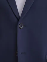 Blazer formal color negro, confeccionado en tela texturada, con solapas clásicas, cierre de dos botones frontales y bolsillos con solapa.
