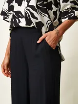 Pantalon tipo palazzo color negro con estampado paisley en tonos beige y blanco, corte holgado y tiro medio.
