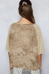 Remera de corte boxy con estampado animal print en el frente y mangas raglán en color gris liso. Presenta un bolsillo frontal y mangas 3/4 con terminación sin costura.