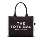 Bolso tipo tote de jacquard color negro con inscripción frontal 'THE TOTE BAG MARC JACOBS' en color blanco. Presenta un diseño de gran capacidad con cierre de cremallera superior, asas dobles para llevar al hombro o en la mano y bordes laterales en contraste con texto.