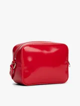 Cartera tipo bandolera de Tommy Jeans con acabado brillante y liso. Presenta un diseño rectangular con cierre de cremallera superior, correa ajustable y una insignia con el logo de la marca grabado en el centro de la parte frontal.