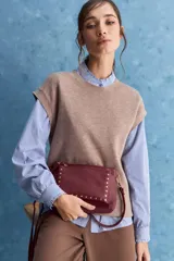 Chaleco de tejido de punto color beige claro, con cuello redondo y diseño de líneas limpias con hombros caídos y terminaciones acanaladas.