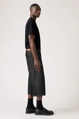 Pantalón capri de denim negro con corte amplio, tiro alto y cinturón de tela con hebilla metálica.