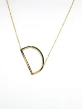 Collar plateado con dije de la letra G mayúscula.