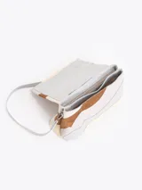 Cartera de hombro con diseño de ondas en combinación de cuero vacuno y descarne en tonos neutros. Presenta una estructura semirrígida, cierre frontal con aplique metálico tipo candado y correa de hombro ajustable.