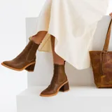 Botas tipo chelsea de cuero vacuno negro, con elásticos laterales, taco cuadrado y punta fina.