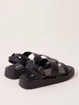 Sandalias negras con plataforma, tiras anchas y hebilla al tobillo.