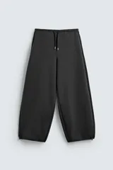 Pantalón de corte baggy fit confeccionado en tejido técnico, con cintura elástica ajustable mediante cordón y bajo con elásticos laterales para ajuste.