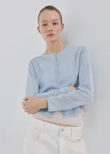 Cardigan de punto fino color celeste, con cuello redondo, manga larga y cierre delantero con botones.