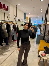 Polera de manga larga en color negro, con cuello alto y costuras decorativas visibles en el frente que realzan la silueta.