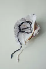 Collar compuesto por múltiples hilos de cuentas de vidrio que imitan perlas en tonos blanco y negro, entrelazados en un diseño dinámico.