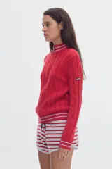 Cardigan de punto color marfil con cierre frontal completo, cuello alto y detalles de rayas en contraste en cuello, puños y ruedo. Presenta diseño de ochos verticales.