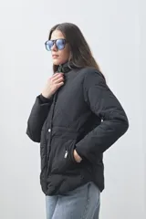 Campera puffer negra con diseño acolchado, capucha integrada y cierre frontal con botones a presión. Presenta puños elásticos y costuras decorativas en el frente.